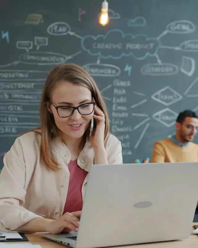 Consultora falando ao telefone enquanto anota informações no notebook